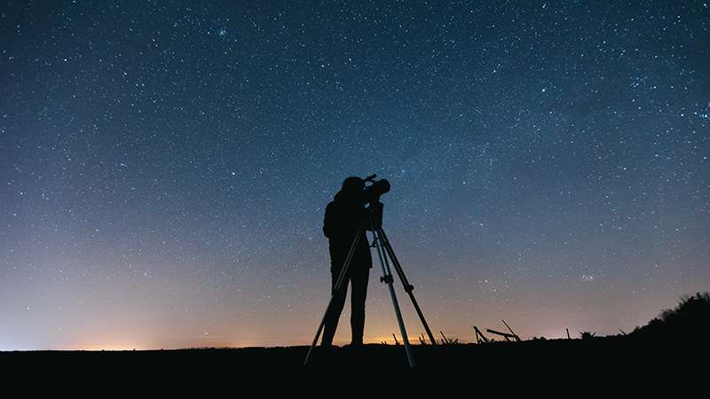 Man using a telescope to look at the night sky